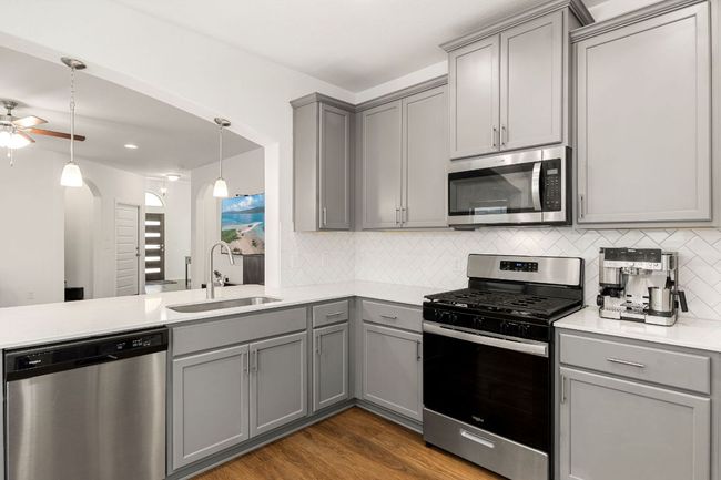 Kitchen with gray cabinetry, appliances with stainless steel finishes, backsplash, and recessed lighting | Image 14