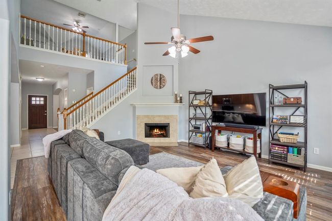 Looking back toward the front entry, this view captures the openness of the layout with a glimpse of the upstairs loft-style game room through the staircase bannister. Just beyond the stairs, a hallway leads to the half bath and a spacious under-stairs closet—perfect for extra storage. | Image 7