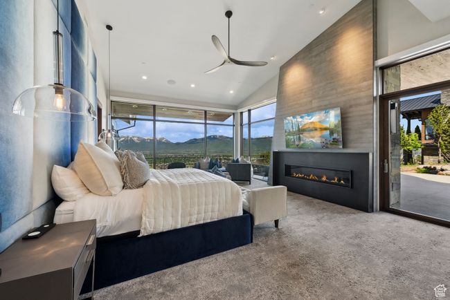 Carpeted bedroom with access to exterior, vaulted ceiling, a glass covered fireplace, and recessed lighting | Image 27