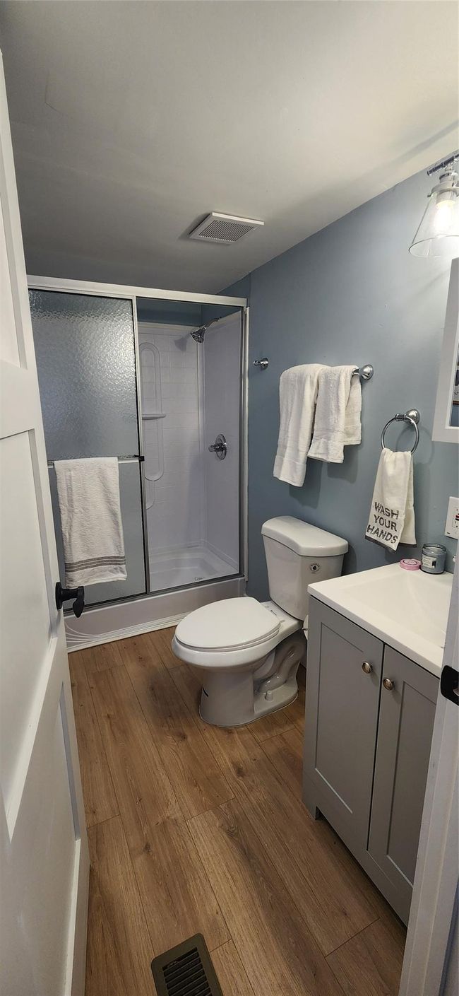 Bathroom featuring visible vents, an enclosed shower, toilet, and wood finished floors | Image 17