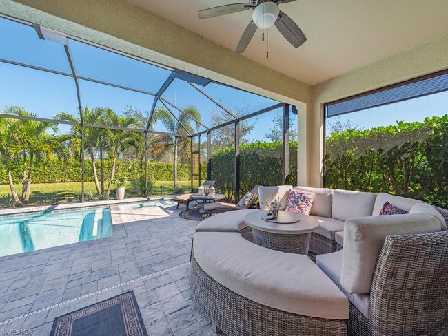 View of patio featuring a ceiling fan, glass enclosure, an outdoor pool, and an outdoor hangout area | Image 10