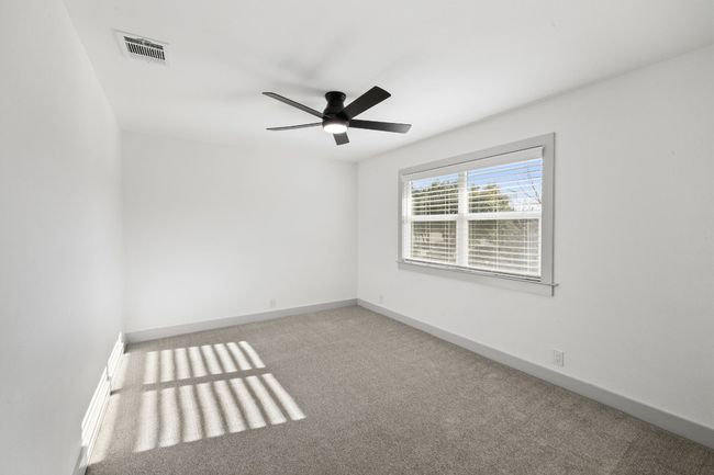 This secondary bedroom has a large sized window, a ceiling fan and built-in shelves. | Image 22