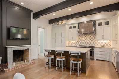 Kitchen with appliances with stainless steel finishes, beamed ceiling, light hardwood / wood-style floors, a center island, and wall chimney exhaust hood | Image 3