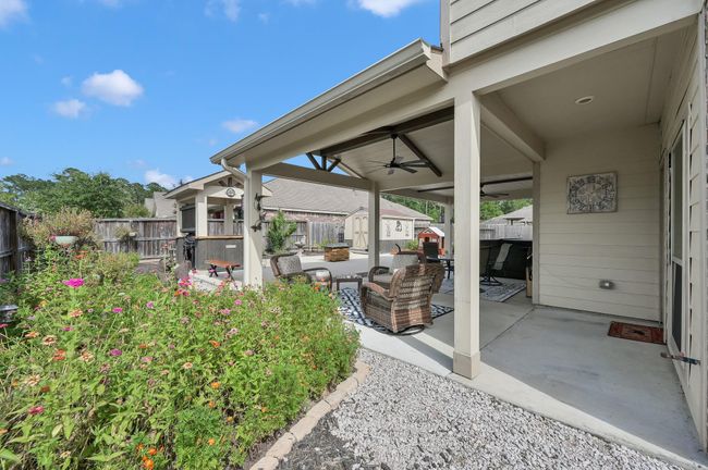 Backyard retreat boasts a large covered patio with fans, BBQ pavilion, lush landscaping, patio extension, and a roomy storage shed. | Image 32