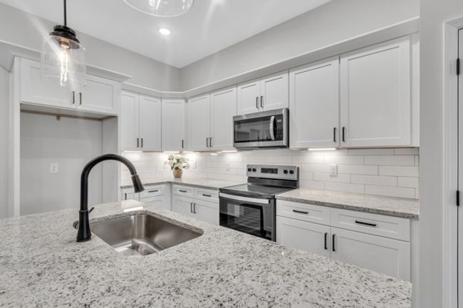 This kitchen is stunning with a large island, granite counter tops, tile back splash and under cabinet lighting. | Image 10