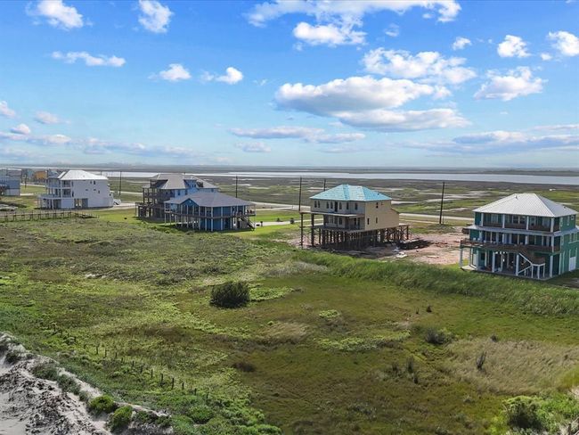 Pictured here: the neighborhood view from your future beachfront deck. 5002 Blue Water Hwy will rise just to the left of the mint-green home (Gulf Palace), offering front-row views of the Gulf and direct access to the beach, all while being just steps from the community’s rec area. | Image 8