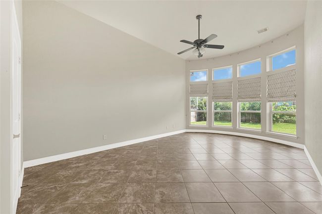 The primary bedroom is expansive, with high ceilings and two rows of windows along a gently curving wall—framing backyard views and infusing the space with light. | Image 23