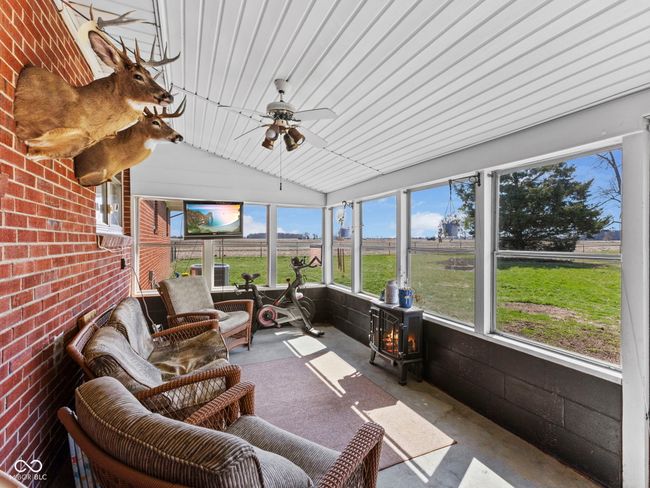 sunroom / solarium featuring a wood stove and a ceiling fan | Image 28