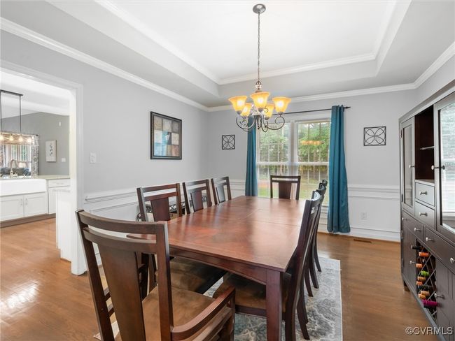 Dining room with a chandelier, wood finished floors, a raised ceiling, molding. | Image 15