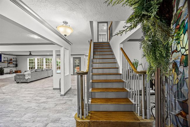 This photo showcases a bright, open-concept living space with a modern staircase featuring wooden steps and white railings. | Image 19
