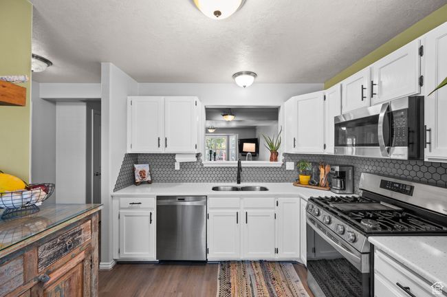 Kitchen with stainless steel appliances, light countertops, and white cabinets | Image 11