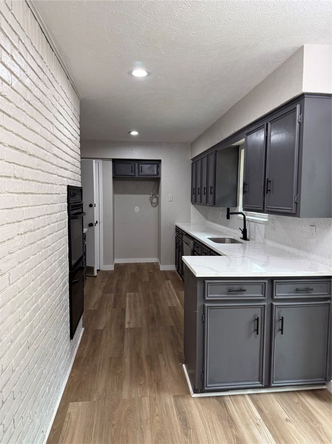 Kitchen featuring dark cabinets, visible vents, light wood-style floors, and a textured ceiling | Image 7
