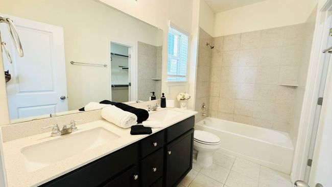 Bathroom featuring double vanity, tile patterned flooring, and shower / tub combination | Image 23
