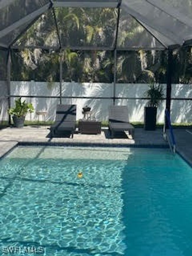 View of swimming pool with glass enclosure, fence, a fenced in pool, and a patio area | Image 29