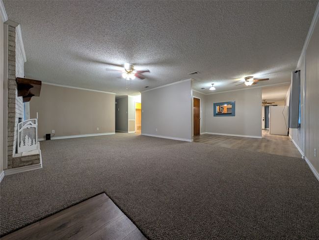 Unfurnished living room with ceiling fan, crown molding, and carpet | Image 14