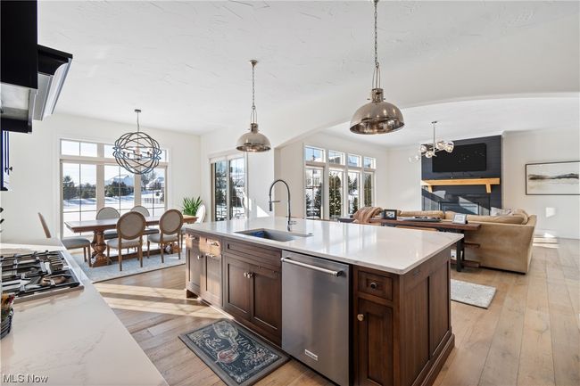 Kitchen with a healthy amount of sunlight, light wood-type flooring, appliances with stainless steel finishes, and decorative light fixtures | Image 12