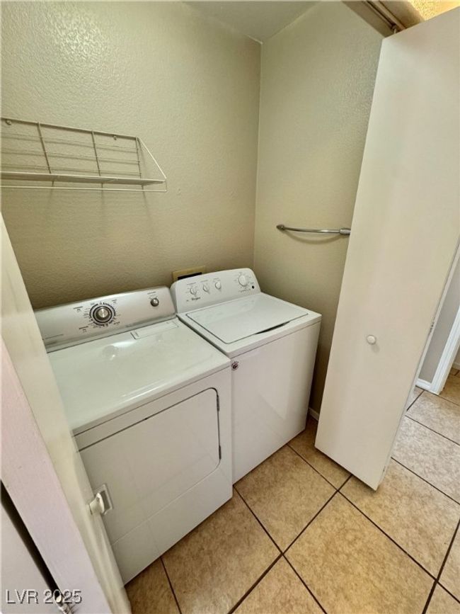 Laundry room featuring separate washer and dryer, a textured wall, laundry area, and light tile patterned floors | Image 13