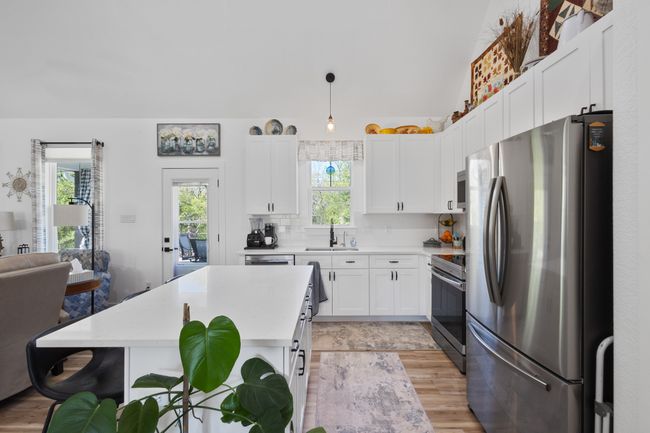 Kitchen with white cabinetry, light countertops, a sink, stainless steel appliances, and backsplash | Image 13