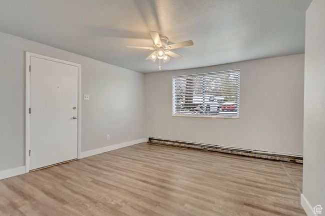 Empty room featuring ceiling fan, wood finished floors, baseboards, and baseboard heating | Image 4