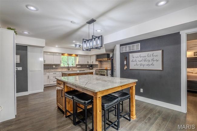 Kitchen featuring dark wood finished floors, white cabinetry, light stone counters, stainless steel range, and recessed lighting | Image 15