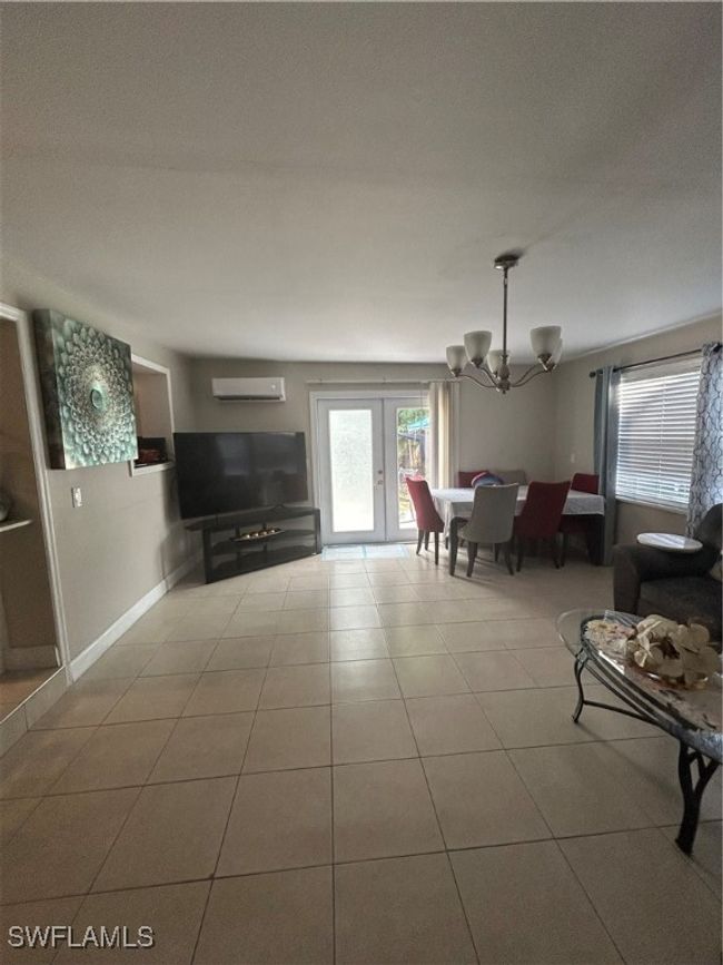 Living area featuring a chandelier, tile patterned floors, and an AC wall unit | Image 5