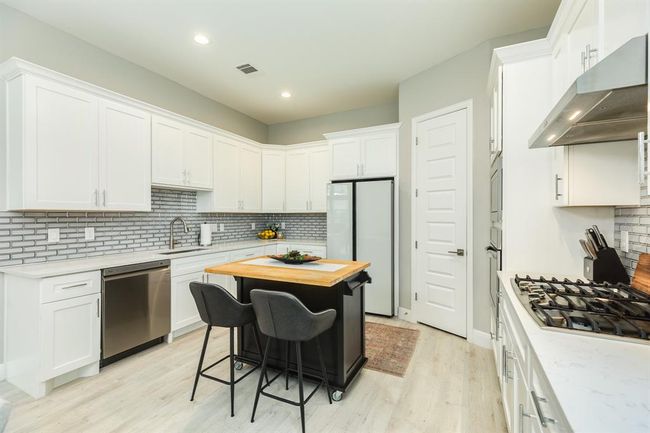 The focal point is a sleek movable island thatnot only provides additional counterspace but also serves as a casualgathering spot. | Image 17