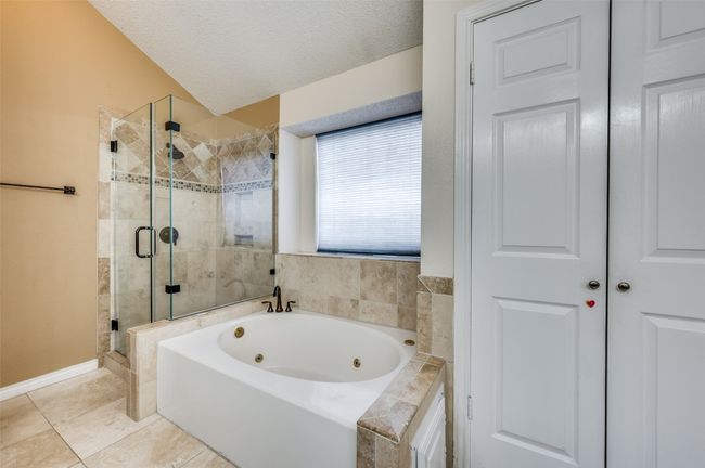 Bathroom featuring a jetted tub, a shower stall, a textured ceiling, and tile patterned floors | Image 13