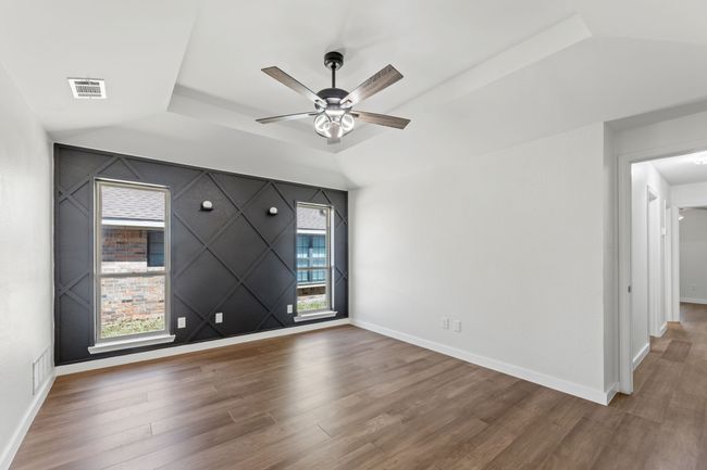 Unfurnished room featuring visible vents, baseboards, ceiling fan, wood finished floors, and lofted ceiling | Image 27