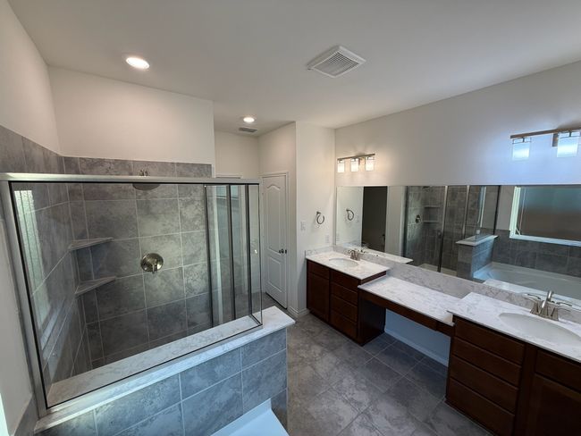 Bathroom with a stall shower, a bath, two vanities, tile patterned flooring, and recessed lighting | Image 15