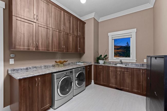 Laundry room with crown molding, light wood finished floors, a sink, washer and dryer, and cabinet space | Image 16