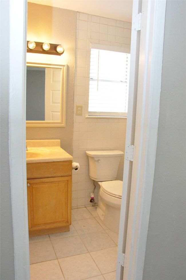 primary bathroom featuring toilet, vanity, tile walls, and tile patterned floors | Image 17