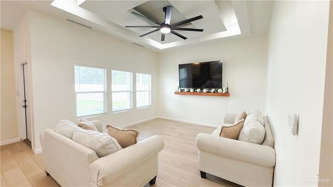 Living area with a tray ceiling, light wood finished floors, and a ceiling fan | Image 9