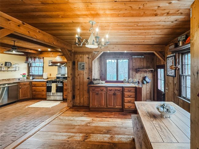 Kitchen featuring wooden ceiling, wooden walls, a sink, appliances with stainless steel finishes, and light wood finished floors | Image 9