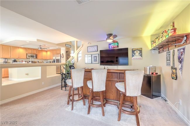 Indoor bar featuring ceiling fan, stainless steel appliances, and light carpet | Image 22