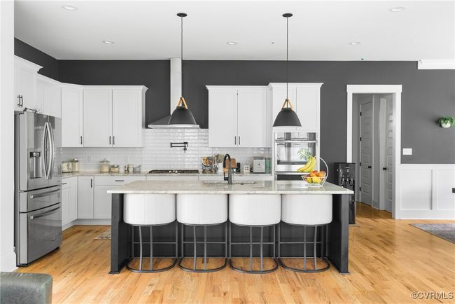 Kitchen with stainless steel appliances, a sink, extractor fan, a breakfast bar, and wainscoting | Image 10