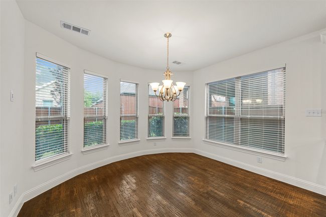 Unfurnished dining area featuring a chandelier, visible vents, dark wood-style floors, and plenty of natural light | Image 10