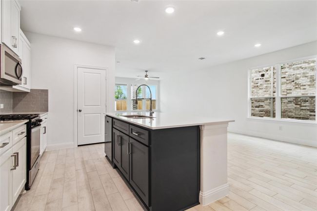 Kitchen featuring white cabinets, tasteful backsplash, recessed lighting, a center island with sink, and appliances with stainless steel finishes | Image 22