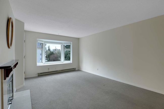 Unfurnished living room featuring a baseboard radiator, carpet, and a textured ceiling | Image 6