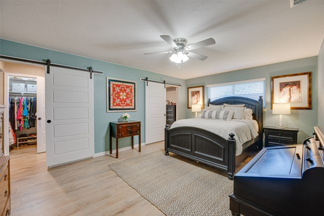 Bedroom featuring a barn door, a spacious closet, a closet, light wood-type flooring, and a ceiling fan | Image 17