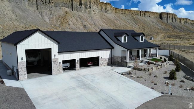 Modern inspired farmhouse featuring covered porch, stone siding, fence, board and batten siding, and a garage | Image 77