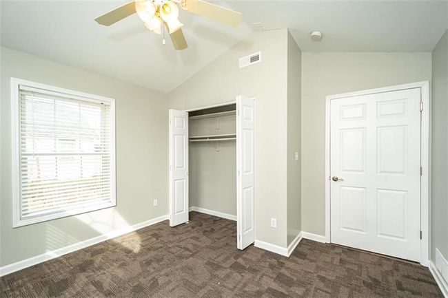 Unfurnished bedroom with vaulted ceiling, visible vents, baseboards, and dark colored carpet | Image 22