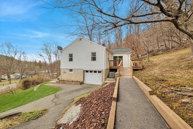 View of side of home featuring a chimney, driveway, a deck, and an attached garage | Image 20