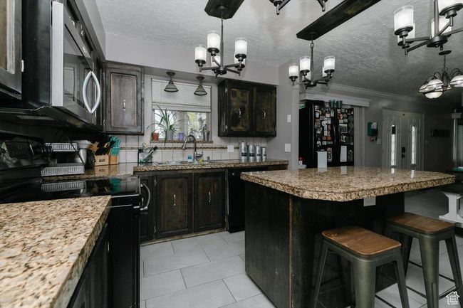 Kitchen with a chandelier, a sink, backsplash, and black appliances | Image 11