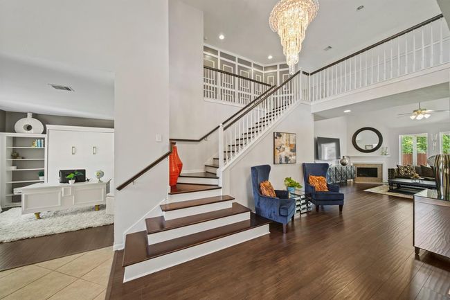 The foyer opens to a graceful staircase and introduces the home’s flowing layout, offering a warm welcome with gleaming floors, and views into the living room and office. | Image 8