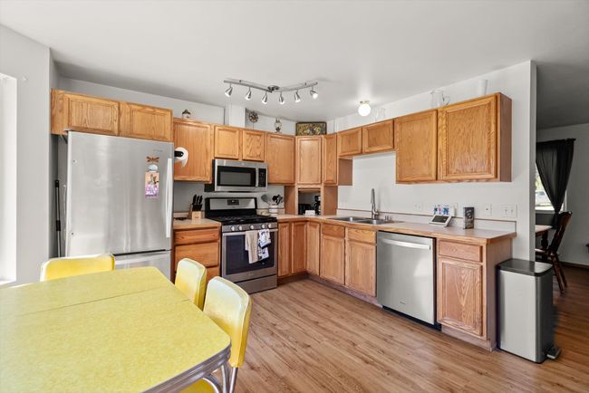 Kitchen with appliances with stainless steel finishes, a sink, light wood-style flooring, and light countertops | Image 27