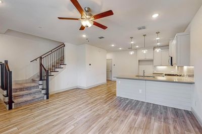 Kitchen with ceiling fan, light wood-type flooring, backsplash, sink, and white cabinetry | Image 3