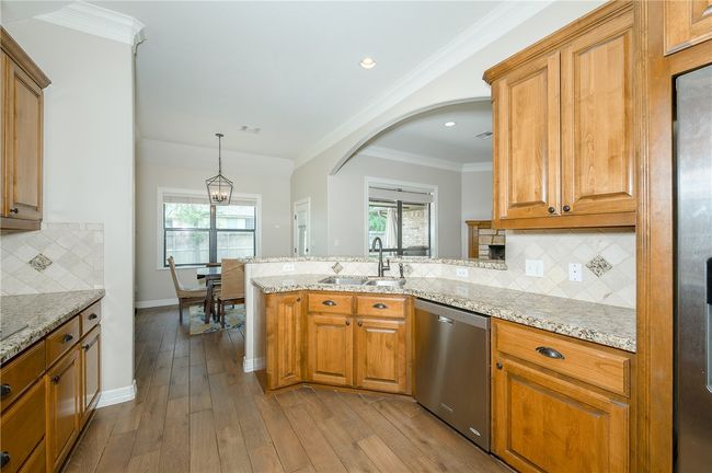 Kitchen with stainless steel dishwasher, a sink, a peninsula, and brown cabinetry | Image 13