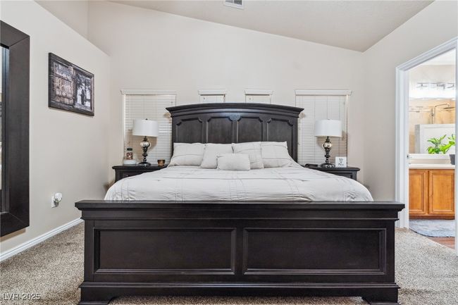 Carpeted bedroom featuring lofted ceiling, connected bathroom, and baseboards | Image 28