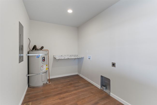 Washroom with electric dryer hookup, dark wood-style floors, secured water heater, laundry area, and baseboards | Image 57