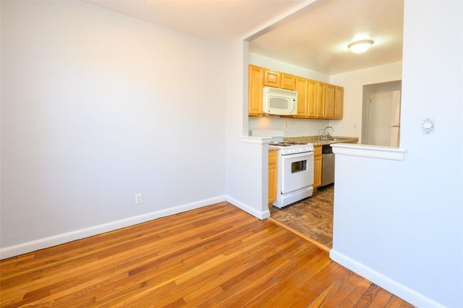 Kitchen with light brown cabinets, dark wood-type flooring, sink, and white appliances | Image 5